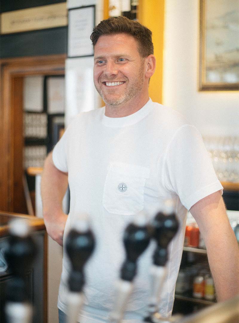 A man smiling behind the bar